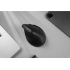 Na zdjęciu znajduje się czarna mysz komputerowa o ergonomicznym kształcie, obok której widoczne są fragmenty srebrnego laptopa i ciemnoszarego tabletu. Tło jest jasne, a na powierzchni widać delikatne cienie.