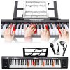Na zdjęciu widoczny jest elektroniczny keyboard z nutami na stojaku, z kilkoma rękami grającymi na klawiszach, oraz akcesoria takie jak mikrofon i zasilacz. Na keyboardzie znajduje się napis: "Keyboard MQ 6151L Czarny".