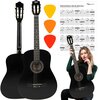 Na zdjęciu znajduje się czarna gitara klasyczna z widocznymi strunami i otworem rezonansowym, obok której umieszczono trzy kolorowe kostki gitarowe oraz planszę z diagramami akordów zatytułowaną "Najważniejsze akordy gitarowe". W prawym dolnym rogu widocz