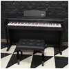 Czarne pianino cyfrowe z widoczną klawiaturą i logo "V-TONE" na pulpicie nutowym, ustawione na tle czarnej ceglanej ściany. Przed pianinem znajduje się czarna, pikowana ławka na biało-czarnej, geometrycznej podłodze.
