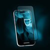 Na zdjęciu widoczny jest smartfon z nałożonym szkłem hartowanym, na ekranie którego znajduje się grafika przedstawiająca tarczę. Tło jest ciemne, z niebieskimi, falistymi wzorami.