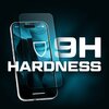 Na zdjęciu widoczny jest telefon z nałożonym szkłem hartowanym, obok którego znajduje się duży napis "9H HARDNESS". Tło jest ciemne, a na ekranie telefonu widoczny jest niebieski wzór oraz ikona tarczy.