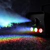 Czarna wytwornica dymu emituje strumień dymu oświetlony kolorowymi światłami LED, tworząc tęczowy efekt na powierzchni. Widoczne są trzy diody LED w kolorach: niebieskim, zielonym i czerwonym.
