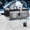 Czarna wytwornica śniegu z napisem "LIGHT4ME SM 900W" na tle zimowego krajobrazu, z widocznym pilotem z przyciskami oznaczonymi literami A, B, C, D. Urządzenie emituje sztuczny śnieg, który unosi się w powietrzu i opada na ziemię.