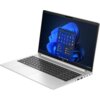 Na zdjęciu widoczny jest srebrny laptop z otwartym ekranem, na którym wyświetlany jest interfejs systemu Windows 11 z ikonami aplikacji. Klawiatura jest pełnowymiarowa, a obudowa posiada kilka portów po jednej stronie.