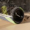 Zdjęcie przedstawia zbliżenie na szczotkę robota sprzątającego z widocznymi kroplami wody unoszącymi się nad nią. Szczotka ma różnokolorowe włosie, w tym zielone i szare pasy, a tło jest rozmyte.