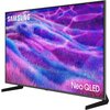 Telewizor z cienką ramką wyświetla kolorowy, abstrakcyjny obraz w odcieniach fioletu i niebieskiego. Na ekranie widoczne są napisy "SAMSUNG" i "Neo QLED".