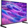 Na zdjęciu widoczny jest telewizor z wyświetlonym kolorowym obrazem przedstawiającym abstrakcyjne, falujące wzory w odcieniach fioletu, różu i niebieskiego. Telewizor stoi na dwóch nóżkach, a jego ekran ma cienką ramkę.