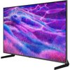 Na zdjęciu widoczny jest telewizor z wyświetlonym na ekranie kolorowym, abstrakcyjnym wzorem w odcieniach fioletu i niebieskiego. Telewizor stoi na dwóch nóżkach, a jego ramka jest cienka i czarna.