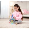 Na zdjęciu dziecko siedzi na dywanie w jasnym pokoju i bawi się lalką SIMBA Kawaii Hi Mia, która ma kolorowe ubranie i niebieskie włosy. Obok lalki znajduje się mały piesek-zabawka i fioletowy grzebień.