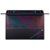 Na zdjęciu widoczna jest klawiatura laptopa z podświetleniem RGB, które zmienia kolory od niebieskiego do różowego. W prawym dolnym rogu znajduje się logo w kształcie stylizowanej litery "M" z fioletowo-niebieskimi liniami.