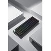 Czarna klawiatura mechaniczna z podświetleniem RGB leży na jasnoszarej, geometrycznej powierzchni. Klawisze mają różnokolorowe podświetlenie, a jeden z klawiszy jest w kolorze miętowym.