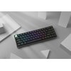 Na zdjęciu znajduje się bezprzewodowa klawiatura z podświetleniem RGB, umieszczona na szarej powierzchni w otoczeniu białych geometrycznych kształtów. Klawisze mają różnokolorowe podświetlenie, a na jednym z klawiszy widoczny jest napis "esc".