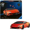 Na zdjęciu znajduje się opakowanie puzzli 3D przedstawiające pomarańczowy samochód sportowy z napisem "Lamborghini Huracan Evo" oraz logo producenta "Ravensburger". Obok opakowania widoczny jest złożony model samochodu z puzzli.