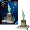 Pudełko przedstawia model 3D Statuy Wolności z efektem świetlnym LED, z widocznymi elementami puzzli unoszącymi się w powietrzu. Na podstawie modelu znajduje się napis "STATUE OF LIBERTY", a na pudełku widnieje logo "Ravensburger".