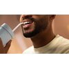 Na zdjęciu widoczny jest irygator w kolorze niebieskim, trzymany w dłoni, z napisem "Philips Sonicare" na obudowie. Osoba używa urządzenia, kierując strumień wody do ust.