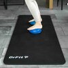 Czarna mata do ćwiczeń z białym napisem "DrFit" leży na podłodze, a na niej znajdują się dwie niebieskie, teksturowane poduszki pod stopami osoby. Podłoga jest wyłożona szarymi płytkami.