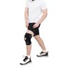 Mężczyzna w białej koszulce i czarnych szortach nosi czarny stabilizator na kolanie z widocznym napisem "DRFIT". Na stopach ma białe buty sportowe z czarnymi i pomarańczowymi akcentami oraz napisem "GAZ".
