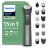 Na zdjęciu znajduje się trymer marki PHILIPS z serii 7000, model Multigroom MG7935/15, obok którego widoczny jest zielony karton z napisem "15 in 1 All-in-One trimmer". Obok trymera znajduje się zestaw różnych nasadek i akcesoriów, a na kartonie widnieje 
