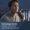 Mężczyzna trzyma golarkę przy twarzy, w tle widoczne są ubrania na wieszakach. Na dole zdjęcia znajduje się tekst: "Technologia SkinIQ Analiza, wskazówki i personalizacja golenia".