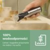 Ręka trzymająca trymer pod strumieniem wody nad umywalką, z widocznym napisem "100% wodoodporności" oraz "Łatwe i wygodne przycinanie na mokro i na sucho" na zielonym tle obok ikony prysznica.