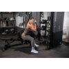 Na zdjęciu znajduje się osoba ćwicząca na maszynie do ćwiczeń INSPIRE FITNESS FT2 PRO z ławką FID7.1 w siłowni. W tle widoczne są hantle, piłki do ćwiczeń oraz półki z ręcznikami.