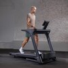 Na zdjęciu znajduje się bieżnia elektryczna INSPIRE FITNESS T4S 2238W 16km/h, na której widoczna jest osoba w stroju sportowym. W tle znajduje się ściana z cegieł, a na bieżni widoczny jest napis "INSPIRE SERIES".