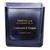 Kwadratowa, ciemnoniebieska świeca z napisem w kolorze złotym: "SORVELLA CANDLE Cashmere & Pepper SIGNATURE".