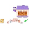 Zestaw figurek ZURU Little Live Pets Mama Surprise Minis zawiera fioletowo-kremową klatkę z przezroczystym pojemnikiem na wodę, wypełnioną żółtymi wiórkami, oraz cztery figurki królików w różnych kolorach i zielony listek. Obok znajduje się karta z ilustr