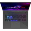 Laptop z otwartym ekranem, na którym widoczna jest grafika z napisem "ROG STRIX" na tle fioletowo-niebieskich świateł. Klawiatura podświetlona jest w kolorach tęczy, z wyróżnionymi klawiszami "QWER" i "ASDF" w odcieniach niebieskiego.