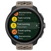 Smartwatch z beżowo-czarnym paskiem wyświetla listę aktywności: "Mountain biking Enduro", "Track running Basic", "Trail running Mountain", "Gravel cycling Power", "Pool swimming Basic". Na dole ekranu widoczne jest logo "SUUNTO".