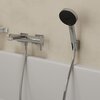 Na zdjęciu znajduje się chromowany wąż prysznicowy podłączony do baterii łazienkowej zamontowanej na ścianie nad wanną. Obok baterii widać uchwyt z zamocowaną słuchawką prysznicową.
