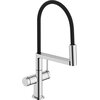 Chromowana bateria kuchenna z czarnym, elastycznym wężem, posiada cylindryczny uchwyt i wylewkę. Na podstawie baterii widoczne jest logo "hansgrohe".