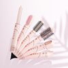 Na zdjęciu znajduje się suszarko-lokówka BEAUTIFLY Multi Styler Stylebliss Rose 50 mm 1200 W z kilkoma różnymi końcówkami, ułożona wachlarzowo na jasnym tle. Na każdej z końcówek widoczne są przyciski oraz napisy "BEAUTIFLY".