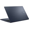 Na zdjęciu widoczny jest zamknięty laptop w kolorze ciemnoniebieskim z logo "ASUS" na obudowie. Laptop ma smukłą konstrukcję, a na jego boku znajdują się różne porty.