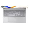 Na zdjęciu widoczny jest otwarty laptop z klawiaturą i touchpadem, na ekranie wyświetla się napis "ASUS Vivobook". Klawiatura jest pełnowymiarowa, a obudowa ma srebrny kolor.