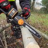 Na zdjęciu widać osobę używającą piły akumulatorowej do cięcia gałęzi. Na ostrzu piły widoczny jest napis "WORX NITRO 12" 30 cm".