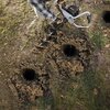 Na zdjęciu widać wiertnicę glebową używaną do wiercenia otworów w ziemi, otoczoną trawą i ziemią. Na urządzeniu widoczny jest napis "WORX".