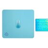 Na zdjęciu widoczna jest morska podkładka z logo SteelSeries w dolnym rogu, na której znajduje się myszka w tym samym kolorze. Obok podkładki znajduje się klawiatura z podświetleniem w odcieniach niebieskiego i żółtego.