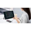 Na zdjęciu widać monitor ZEUSLAP Z15ST 15" z wyświetlonymi ikonami aplikacji, podłączony do smartfona za pomocą kabla. Obok monitora osoba trzyma filiżankę z napojem, siedząc przy białym stole.
