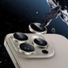 Na zdjęciu widoczny jest fragment smartfona z trzema obiektywami aparatu, na które nakładana jest złota nakładka ochronna. W tle znajduje się przestrzeń kosmiczna z asteroidą.