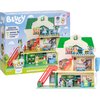 Na zdjęciu znajduje się zestaw figurek "BLUEY Supermarket BLU18918" przedstawiający dwupoziomowy supermarket z czerwonymi schodami, kasą, półkami z produktami oraz figurkami postaci. W tle widoczne jest opakowanie z napisem "BLUEY", "ENDLESS SHOPPING FUN!