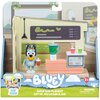 Zestaw do zabawy przedstawia figurkę niebieskiego psa z czerwonym kubkiem, stojącą obok blendera i lady z dwoma kubkami. Na opakowaniu widnieje napis "BLUEY Juice Bar Playset Set de Jeu Le Bar à Jus" oraz ostrzeżenie o małych częściach.