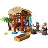 Zestaw LEGO przedstawia chatkę w wiosce z elementami takimi jak palma, łódka i deska surfingowa z napisem "LEGO". Na chatce widoczny jest napis "partys".