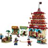 Zestaw LEGO przedstawia scenę z budynkami i postaciami, w tym dużą, wielopoziomową strukturę z napisem "ARLONG PARK" oraz mniejsze budowle z napisami "SHOOTING GALLERY" i "SHARK ATTACK". Wokół znajdują się różne elementy dekoracyjne, takie jak drzewa i ła