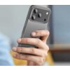 Przezroczyste etui ochronne na smartfonie, które ma wycięcia na trzy obiektywy aparatu i lampę błyskową. Etui jest trzymane w dłoni na tle rozmytego wnętrza.