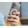 Przezroczyste etui na telefon z widocznym okręgiem MagSafe trzymane w dłoni, z widocznymi dwoma obiektywami aparatu i lampą błyskową. W tle rozmyte elementy wnętrza.