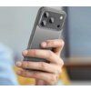 Przezroczyste etui ochronne na smartfonie, które ma widoczne trzy obiektywy aparatu i lampę błyskową. Telefon jest trzymany w dłoni na tle rozmytego wnętrza.