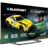 Na zdjęciu widoczny jest telewizor z wyświetlonym obrazem żółtego samochodu wyścigowego oraz tekstem: "BLAUPUNKT", "Google TV", "4K", "QLED", "MEMC", "Dolby ATMOS", "Series QBG6000", "43”". W tle znajduje się zbliżenie na twarz osoby w kasku, a obok logo 