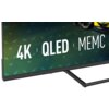 Na zdjęciu widoczny jest fragment telewizora z napisem "4K | QLED | MEMC" na ekranie. Obudowa telewizora jest w kolorze ciemnym, a tło ekranu ma gradientowe odcienie zieleni i niebieskiego.